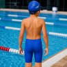 Barn i blå jammer badbyxor från Speedo bakifrån vid poolkant för simning och träning
