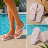 Ljusrosa flipflops för dam med vitt palmbladsmönster och matchande rosa remmar.