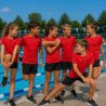 Sex barn och juniorer värmer upp i röda Speedo Veeti T-shirts vid en utomhuspool